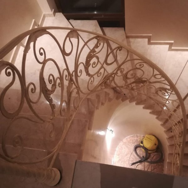 Винтовая лестница из мрамора с коваными перилами 